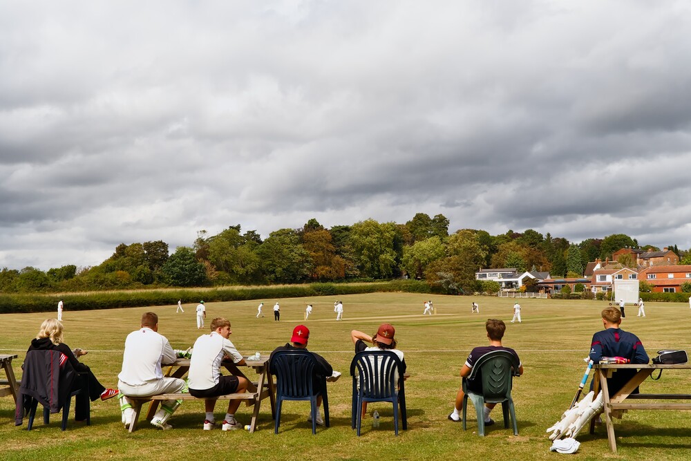 A cricket team watch a cricket match.